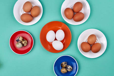 Chicken and quail eggs isolated on turquoise background.の写真素材