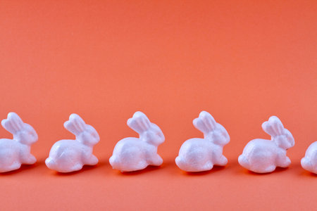 Row of ceramic rabbits on orange background.の写真素材