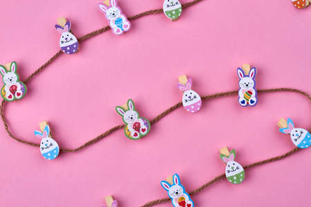 Brown thread and decorative easter rabbits on pink background.