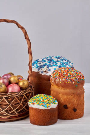 Wicker basket full of decorative easter eggs and cakes with icing.