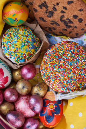 Colorful easter eggs and holiday cakes on a tablecloth.の写真素材