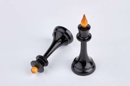 Black queen chess piece stands near fallen chess piece.