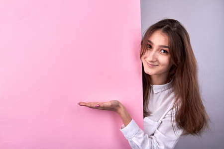 Young girl presenting copy space on a pink wall.の写真素材
