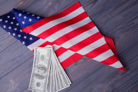 Fan of dollar banknotes and flag of the usa on wooden desk.の写真素材