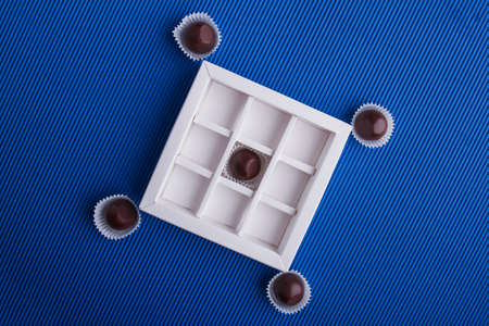 Top view flat lay brown chocolates on blue background.
