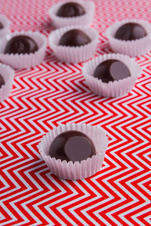 Vertical shot reflective brown chocolate candies close-up.