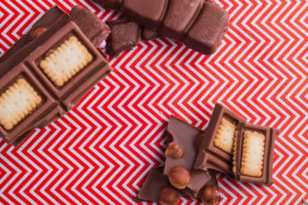 Top view chocolate bar pieces with chunky cookies and hazelnuts.