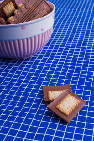 Chocolate bar pieces and bowl on a blue checkered background.の写真素材
