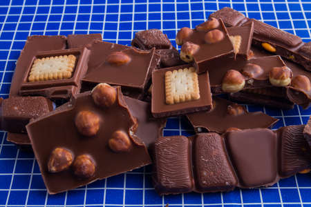 Mix of various cracked chocolate on blue checkered background.