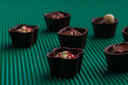 Close-up sweet chocolate candies on relief green background.