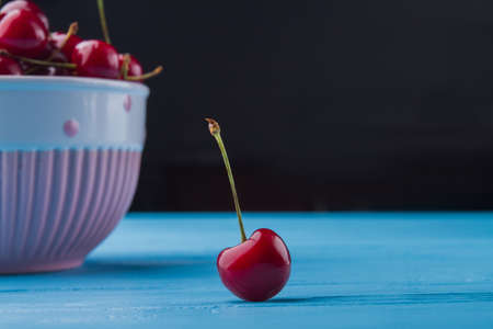 Close-up fresh ripe cherry on blue wooden desk.の写真素材