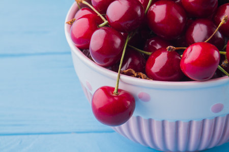 Close-up delicious sweet red cherries on blue wooden background.の写真素材
