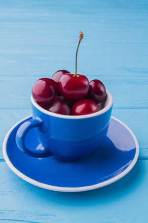 Vertical shot of blue cup full of fresh red cherries.の写真素材