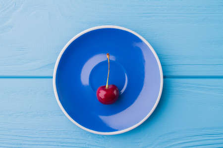 Top view flat lay red cherry on blue plate.