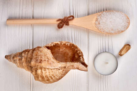 Spoon with seashell and candle top view flat lay.