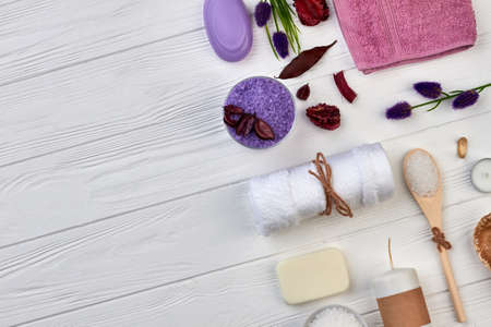 Top view towel with salt and soap on white wooden desk.