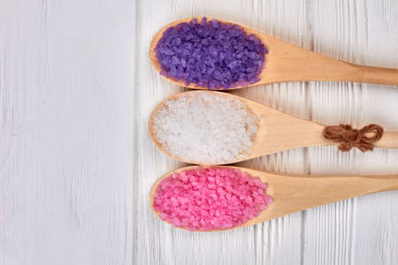 Spoons with colored bath salt on white wooden desk.の写真素材