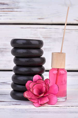 Stack of polished black stones with flower stone and lotion.