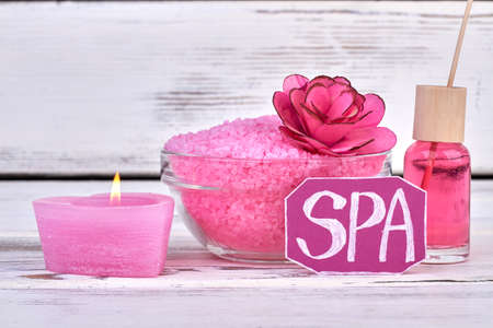 Burning candle with pile of salt and bottle of oil.の写真素材