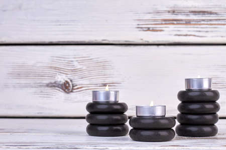Stacks of black stones with burning candles still life.の写真素材