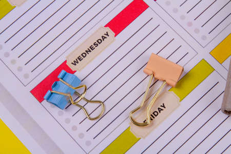 Week calendar and colored binder clips close-up.の写真素材
