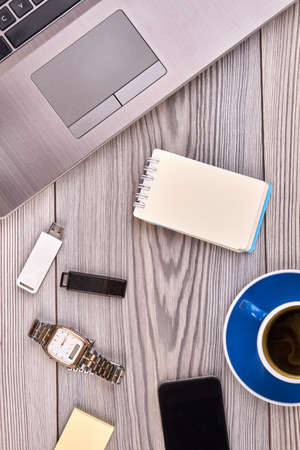 Vertical shot top view flat lay office workdesk on white table. Blank notepad with laptop and watch...
