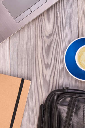 Workdesk accessories on white wood and copy space. Laptop with cup of coffee and black leatehr bag.の写真素材
