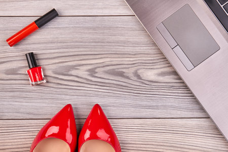 Red shoes with mascara and lacquer with laptop. Top view flat lay copy space.の写真素材