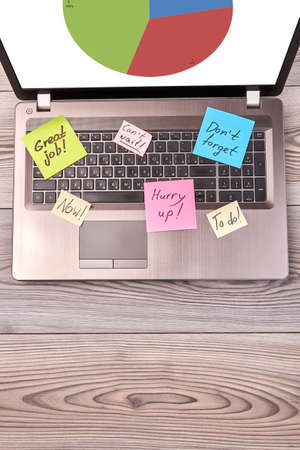 Laptop device with chart statistic diagram and sticky notes. Vertical shot top view.の写真素材