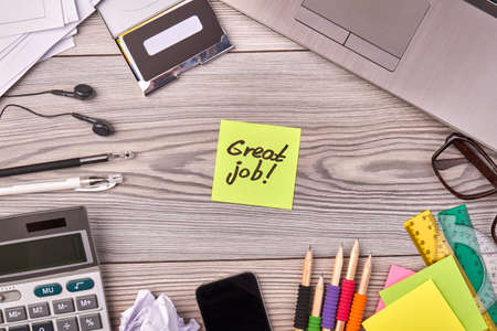 Top view flat lay office stuff and sticky note with great job writing. Calculator with laptop and...