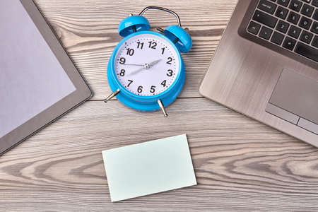 Alarm clock with blank paper for copy space on wooden desk. Top view flat lay.
