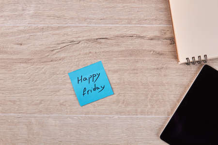 Happy friday handwriting with tablet and notepad. White wood background.の写真素材