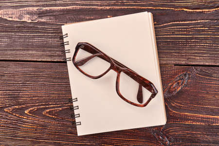 Top view flat lay notepad with glasses. Brown wooden desk background.の写真素材