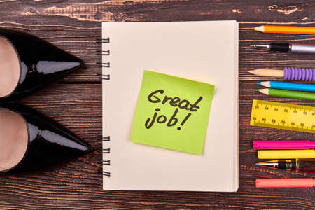 Great job concept flat lay top view. Sticky note with notepad and shoes. Set of pencils and pens.の写真素材