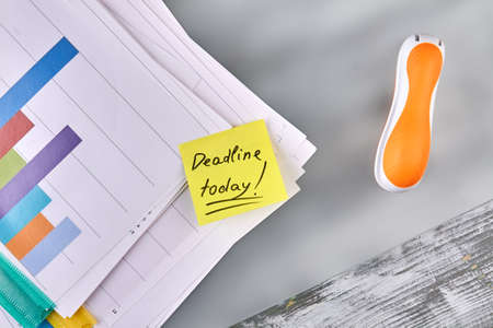 Stapler with work papers and sticky note. Deadline today concept.