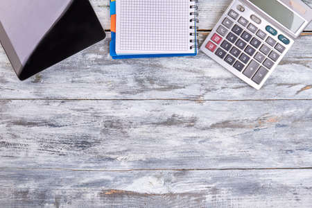 Tablet device with notepad and calculator on wood. Gadgets and copy space.