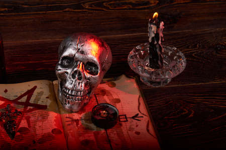 Metallic humans skull with candles and satanic bible with blood. Antichrist wicca satanic ritual with pentagram.の写真素材