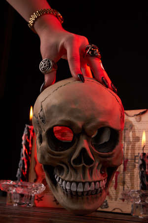 Vertical shot hand over the humans skull on black background. Antichrist satanic ritual concept.の写真素材