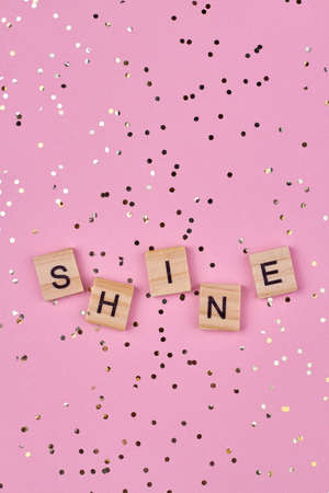 Top view of word SHINE written on wooden cubes on pink background. Flat lay composition.の写真素材