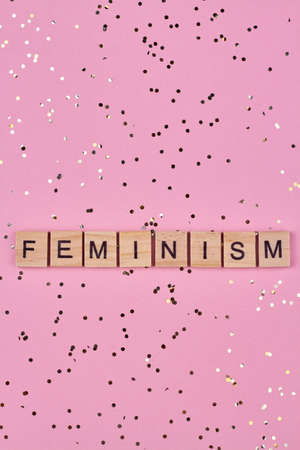 Wooden blocks with written text feminism on pink background. Top view and flat lay.の写真素材