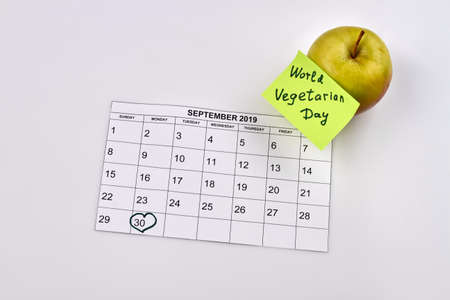Green apple and sticker note with world vegetarian day. Outlined thirty day of september in the...
