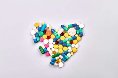 Heart of pills and capsules isolated on white background. Top view flat lay.の写真素材