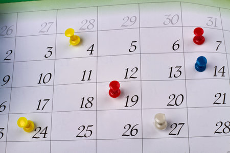Many colorful push pins on a monthly paper calendar page. Deadlines and events planning concept.の写真素材
