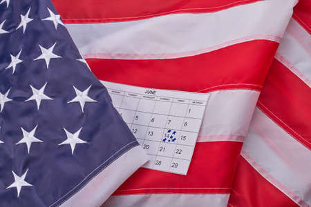 Close-up large fabric us flag and calendar with marked june 14th. Patriotism and independence concept.の写真素材