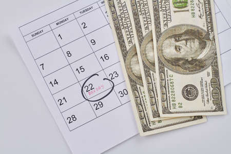Pay day concept. Calendar with money on white background. Top view flat lay.の写真素材