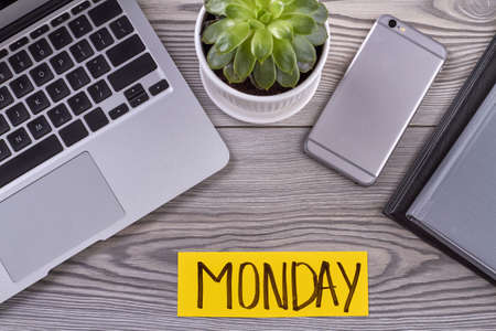 Top view electronic devices and flowerpot on wooden desk. Monday concept flat lay.の写真素材