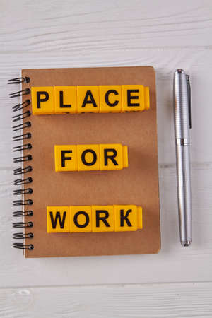 Vertical shot top view notepad with pen. White wooden desk. Place for work concept.の写真素材