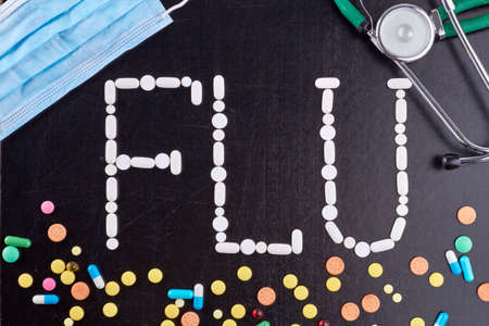 Top view flat lay flu concept on blackboard. Pills with face mask and stethoscope.の写真素材