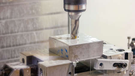 Washing a cut metal cnc drilling machine close-up. Water flow on the drill and metallic block.