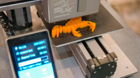 Top view fast speed motion 3d printer is making a yellow figure. Process of creating a dinosaur model.の写真素材